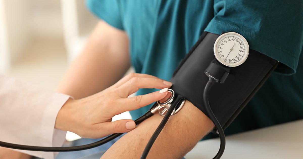 A close-up of a doctor taking a person's blood pressure. The cuff is around the person's left arm and has a gauge on the front.